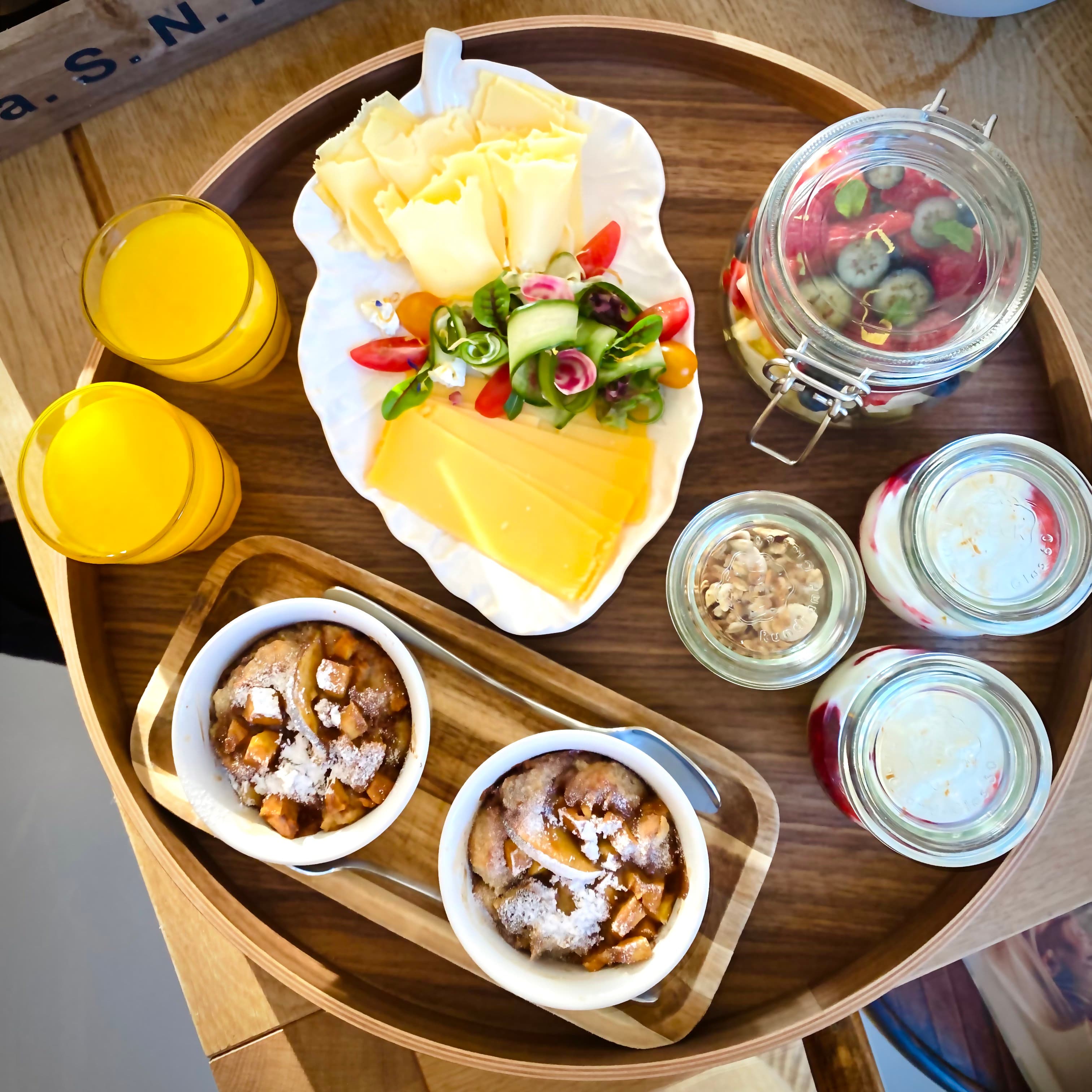 Frühstückstablett für zwei mit Käse, frischem Gemüse, Obst, Joghurt, Orangensaft und warmen Apfelgerichten im Romantic Wellness B&B.