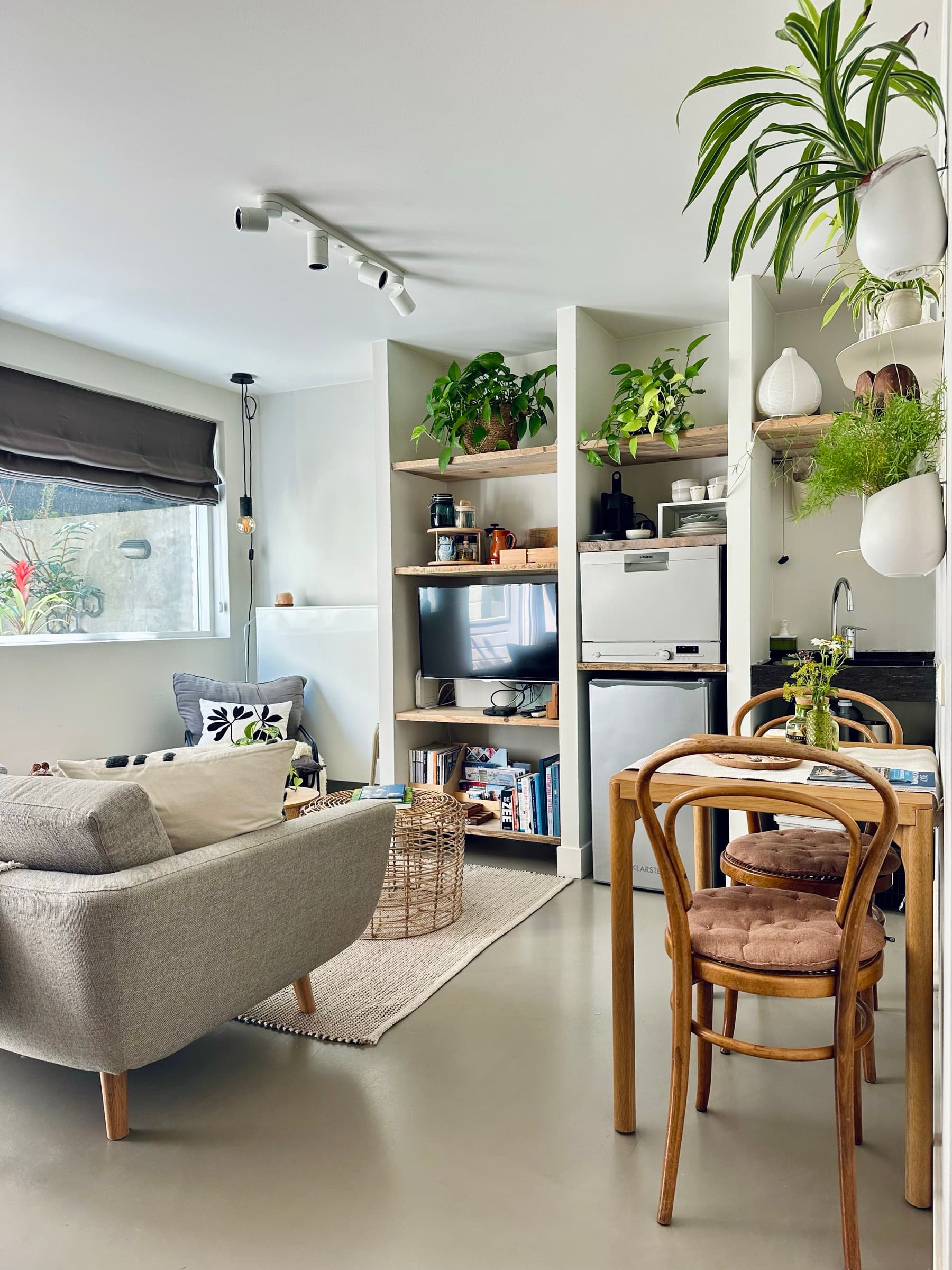 Cocina compacta y salón de la casa privada Romantic Wellness B&B en Noordwijk, con cafetera, nevera y mesa de comedor para dos.