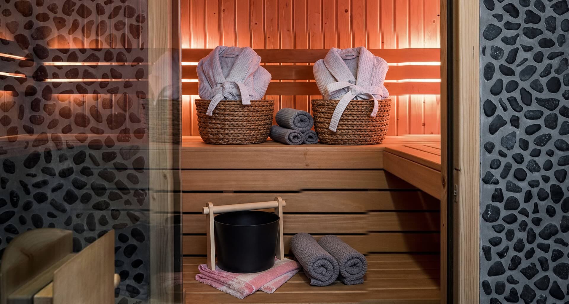 Private holzverkleidete Sauna im Romantic Wellness B&B mit Bademänteln, gefalteten Handtüchern und einem hölzernen Saunaeimer.