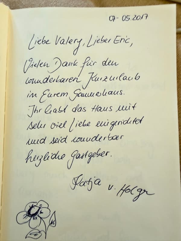 Handwritten German guestbook note thanking Valery and Eric for a wonderful short break, with a blue ink flower drawing.