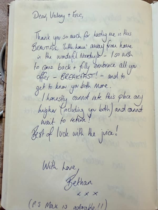 Handwritten English guestbook note praising the beautiful little home, breakfast and hosts, with a postscript about Max the dog.