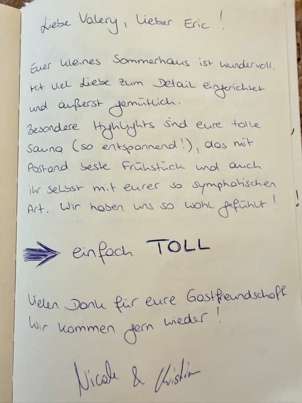 Handwritten German guestbook review praising the cosy summer house, sauna, breakfast and hosts, with a bold arrow pointing to ‘einfach TOLL’.