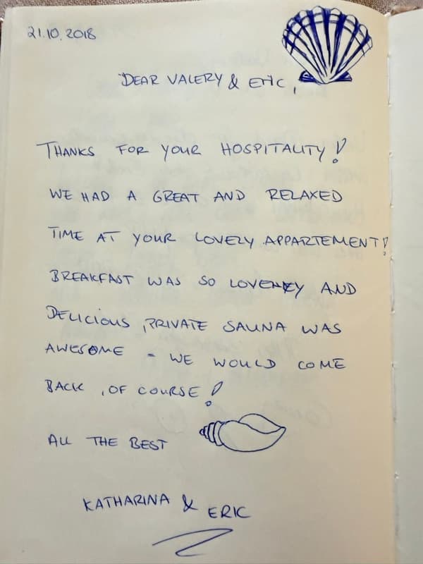 Handwritten English guestbook note thanking the hosts for a relaxing stay, delicious breakfast and private sauna, decorated with two seashells.