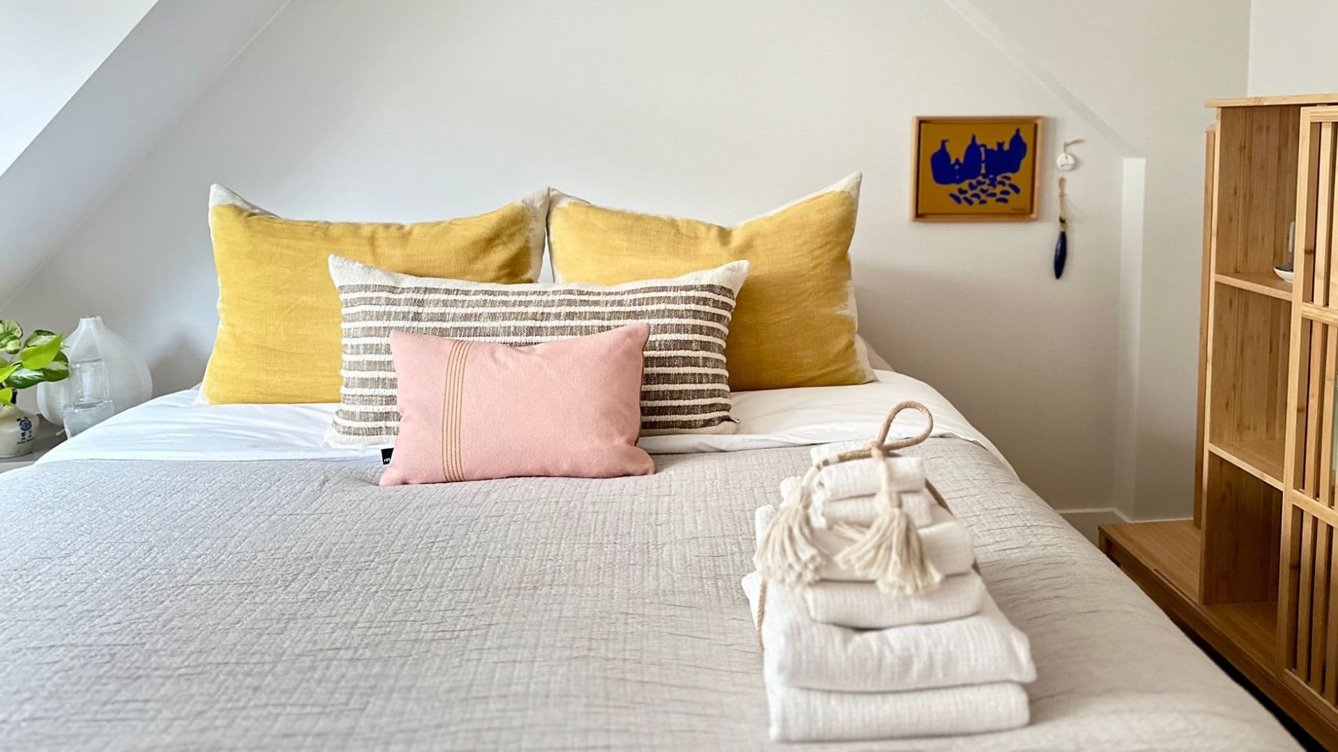 Luminoso dormitorio abuhardillado de Romantic Wellness B&B con cama doble preparada, cojines de colores y toallas dobladas.