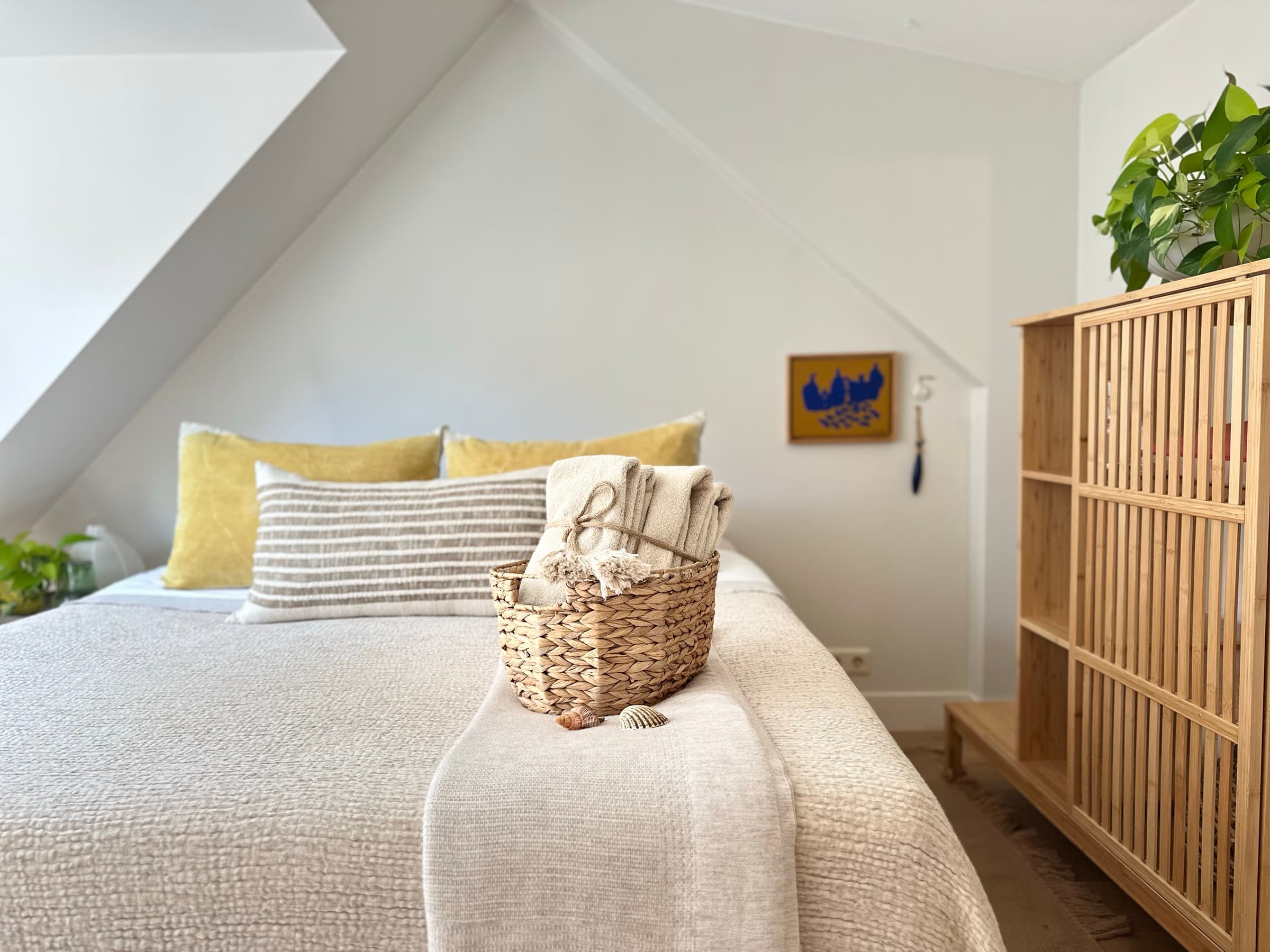 Romantic attic bedroom for two at Romantic Wellness B&B in Noordwijk, with warm natural textiles and fresh towels on the bed.