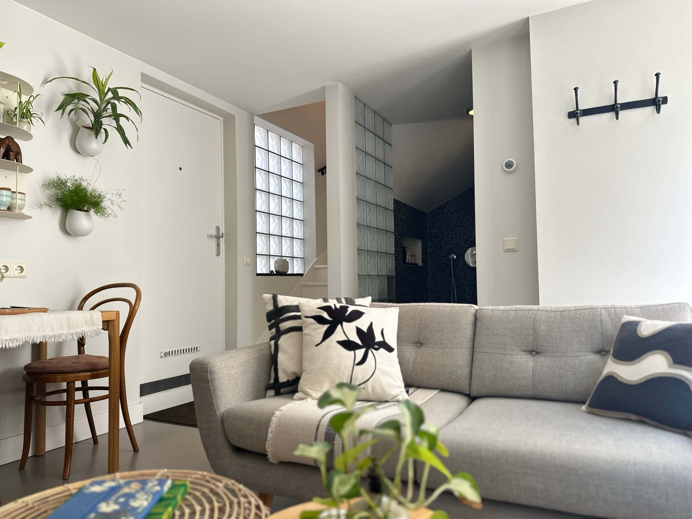 Cosy living room in the private Romantic Wellness B&B guesthouse in Noordwijk, with a grey sofa, dining table and rain shower beyond.