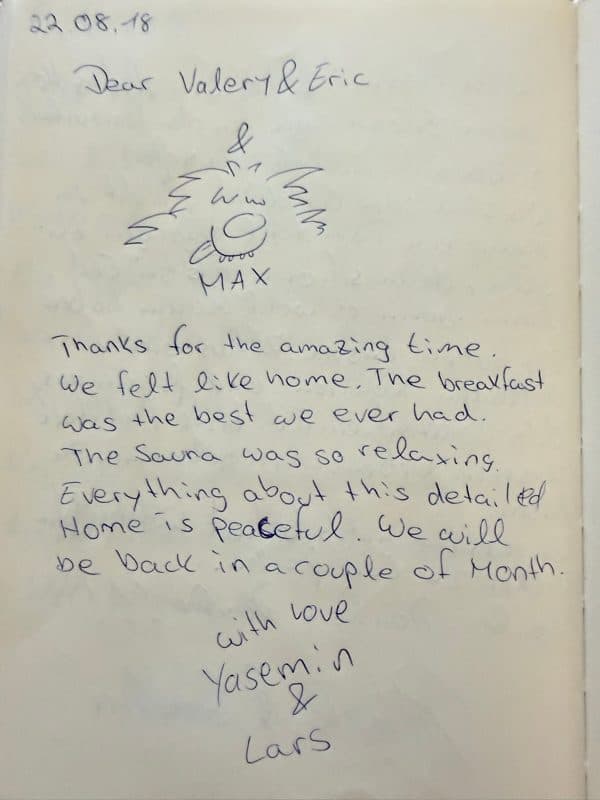 Handwritten English guestbook note praising the breakfast, sauna and peaceful home, beneath a playful drawing of Max the dog.
